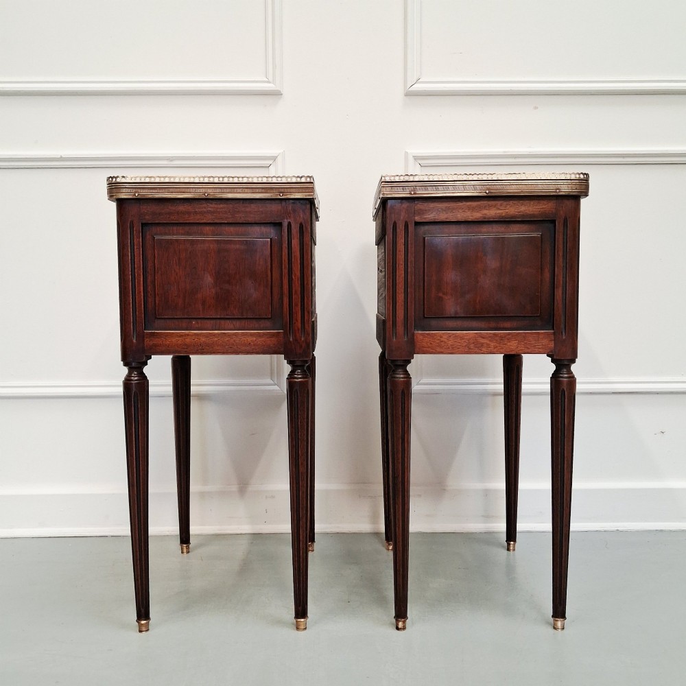 A pair of slim dark wood French bedside tables featuring fluted legs, brass galleries, two drawers, and inset marble tops. View II