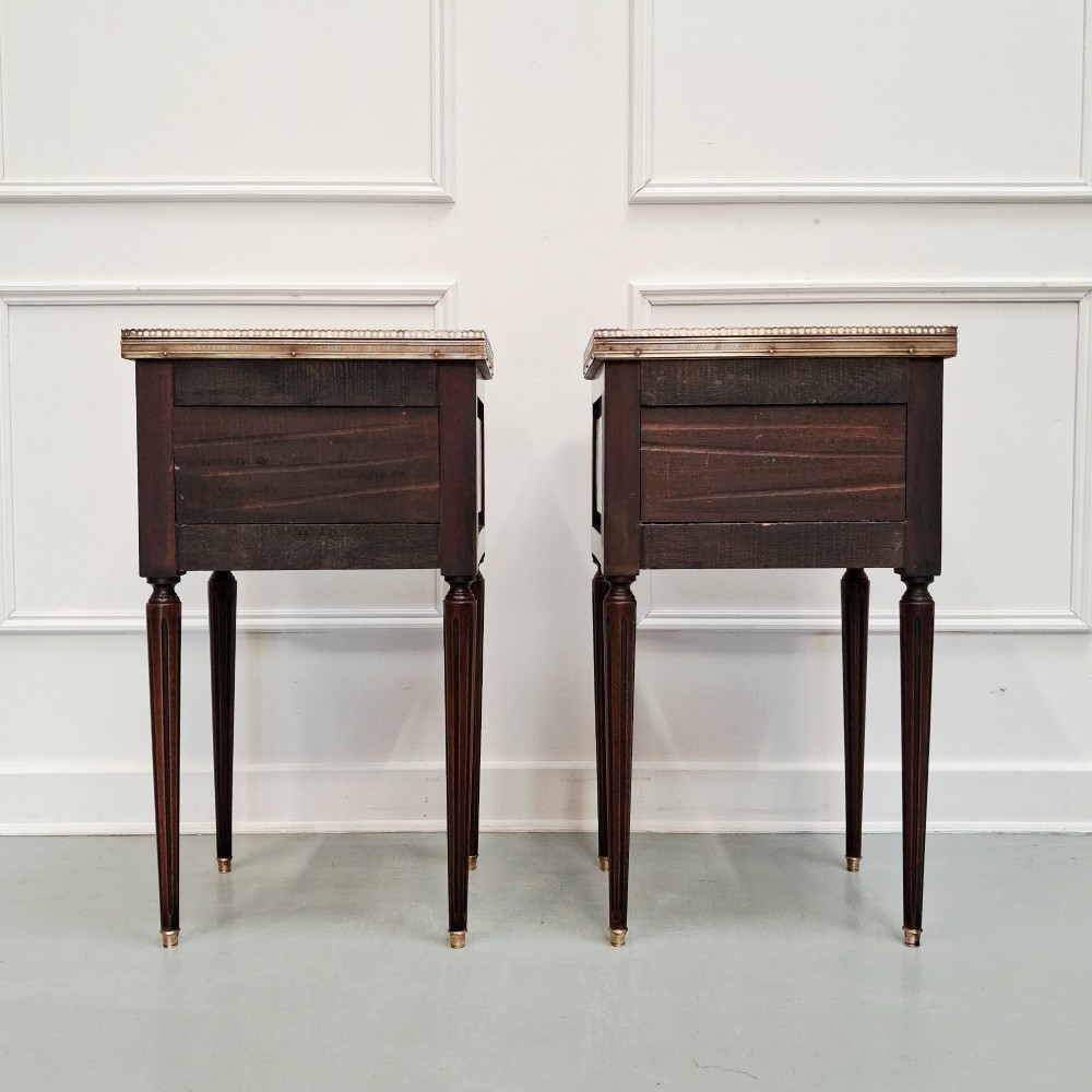 A pair of slim dark wood French bedside tables featuring fluted legs, brass galleries, two drawers, and inset marble tops. View III