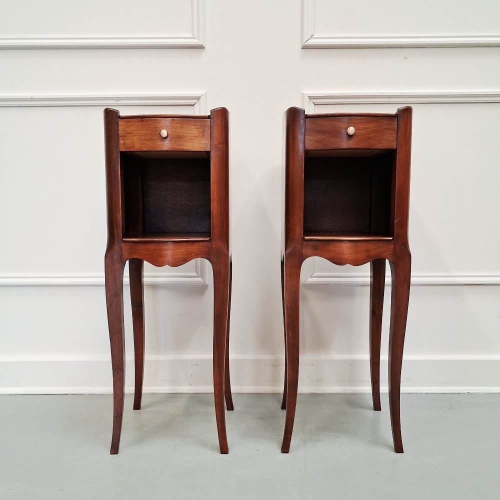 A pair of tall French cherry wood bedside tables with single drawers, open storage niches, and slender cabriole legs.