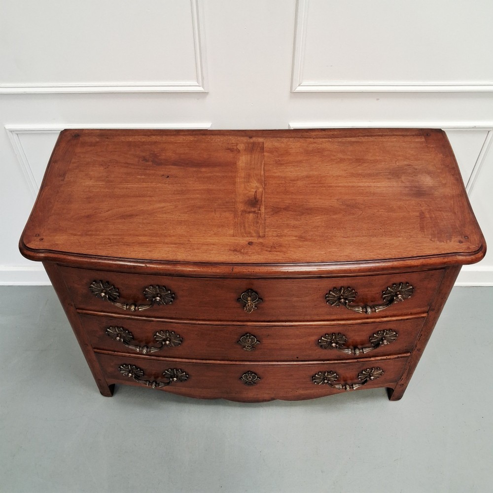 A French country walnut commode featuring three full-width drawers with ornate brass hardware and a scalloped lower apron. View VI