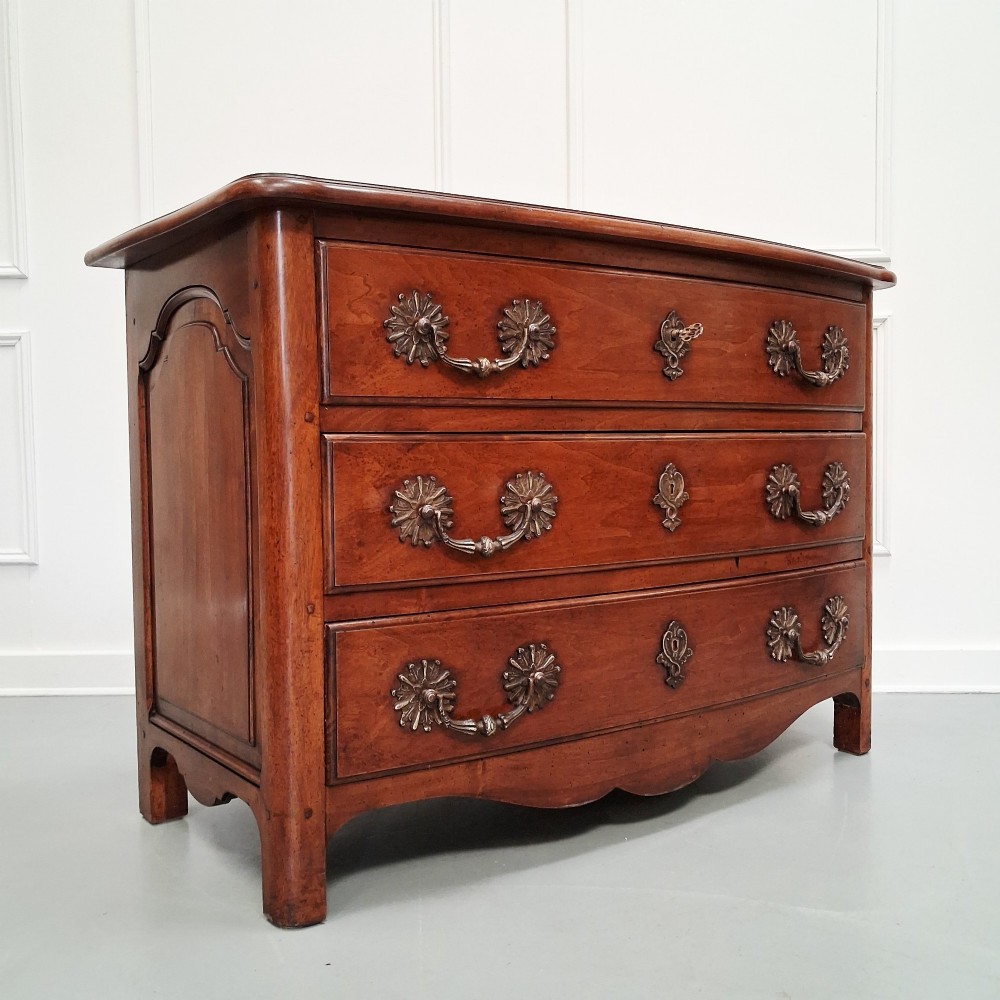 A French country walnut commode featuring three full-width drawers with ornate brass hardware and a scalloped lower apron. View VII