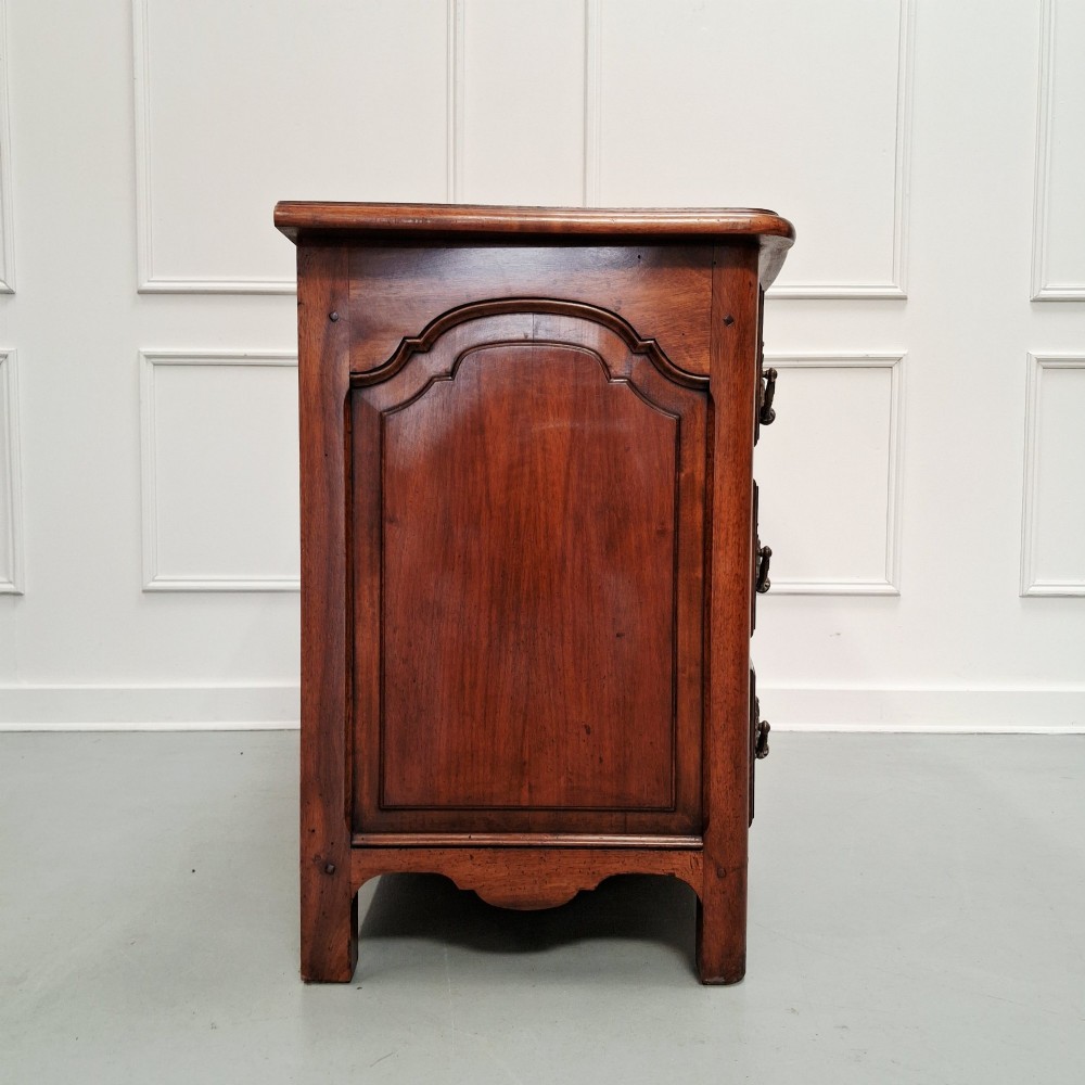 A French country walnut commode featuring three full-width drawers with ornate brass hardware and a scalloped lower apron. View VIII