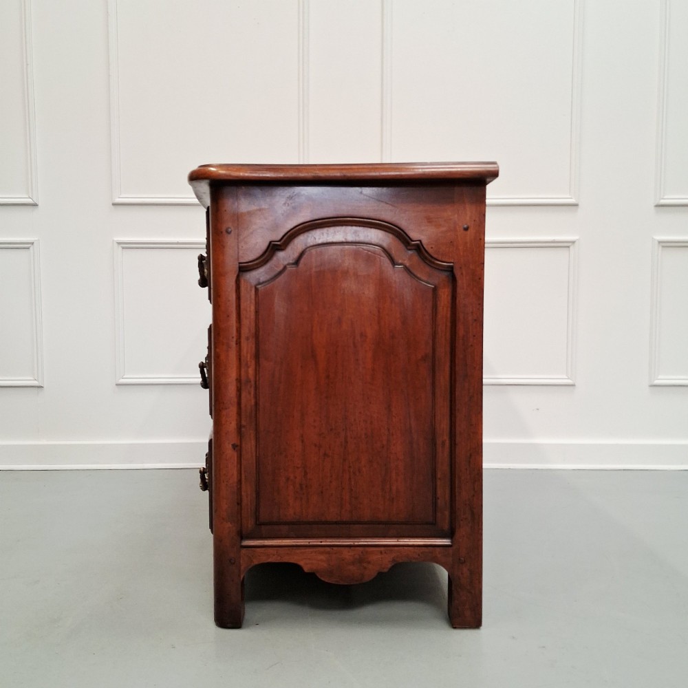 A French country walnut commode featuring three full-width drawers with ornate brass hardware and a scalloped lower apron. View X