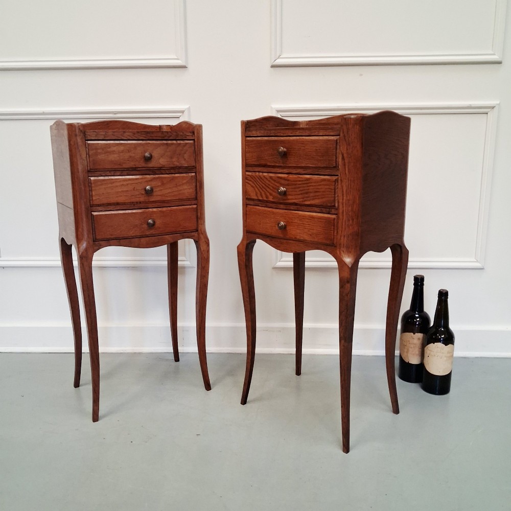 A matching pair of tall French oak bedside tables with slender cabriole legs, three drawers each, and metal knobs. View II