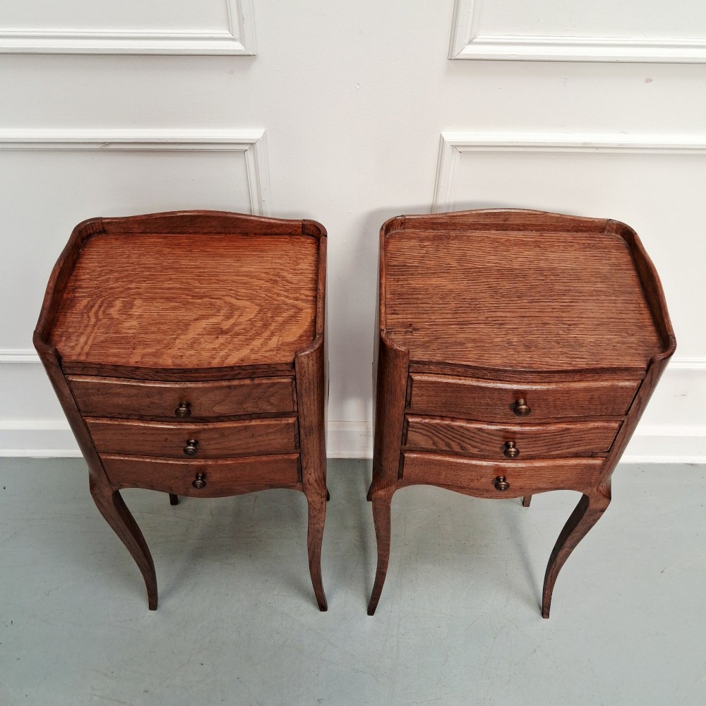 A matching pair of tall French oak bedside tables with slender cabriole legs, three drawers each, and metal knobs. View III
