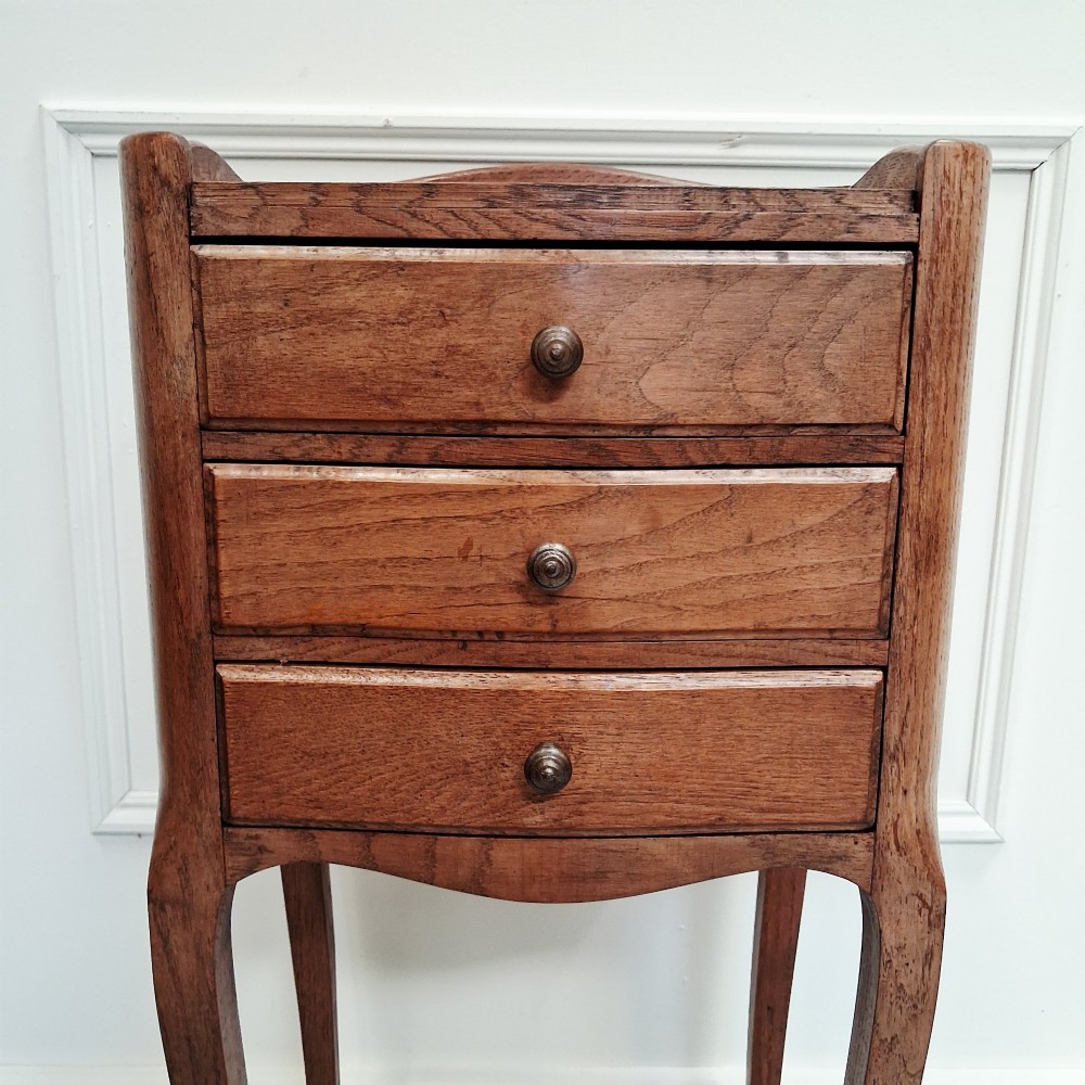 A matching pair of tall French oak bedside tables with slender cabriole legs, three drawers each, and metal knobs. View IV
