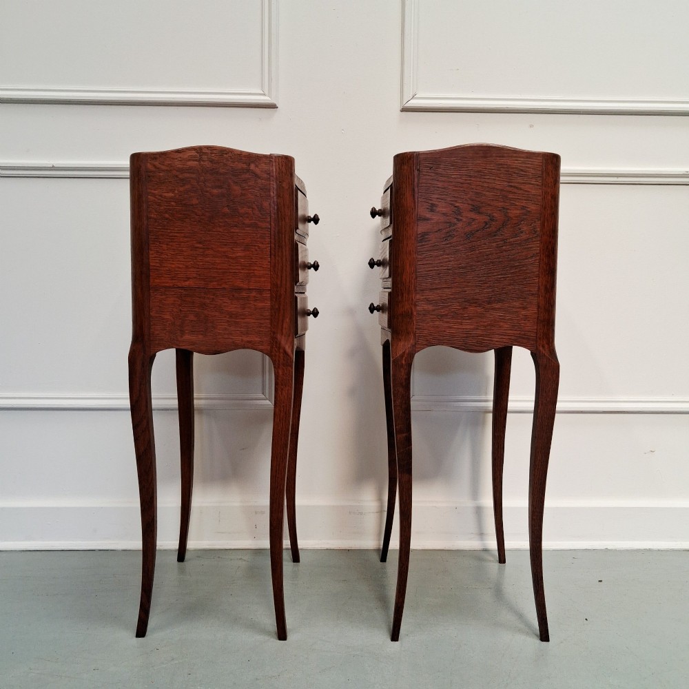 A matching pair of tall French oak bedside tables with slender cabriole legs, three drawers each, and metal knobs. View V