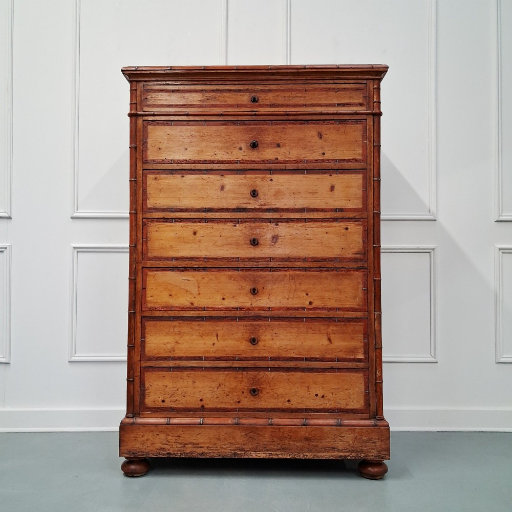 A tall 19th-century French wooden semainier chest featuring seven drawers framed by turned faux bamboo mouldings and supported by bun feet.