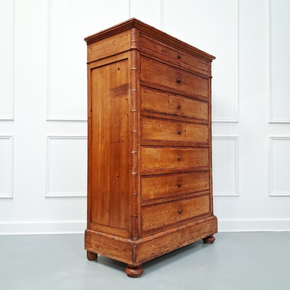 A tall 19th-century French wooden semainier chest featuring seven drawers framed by turned faux bamboo mouldings and supported by bun feet. View IV
