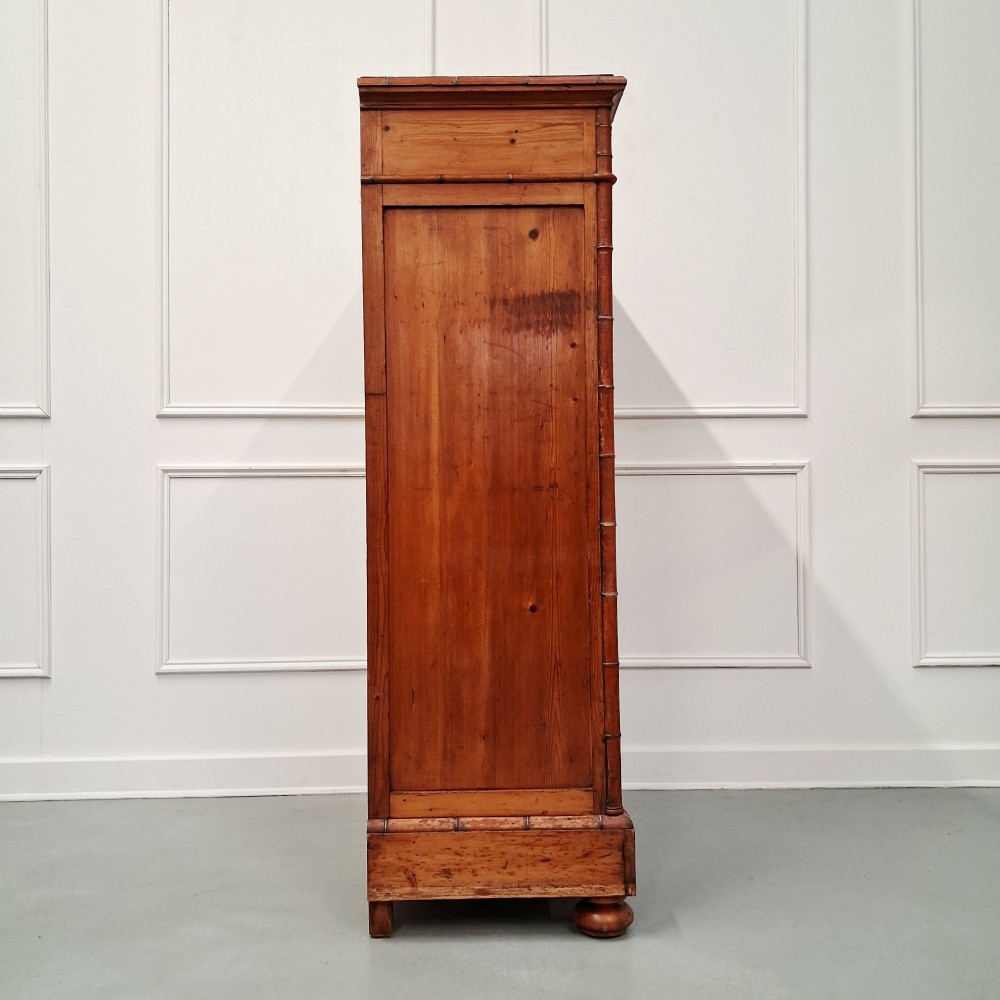 A tall 19th-century French wooden semainier chest featuring seven drawers framed by turned faux bamboo mouldings and supported by bun feet. View V