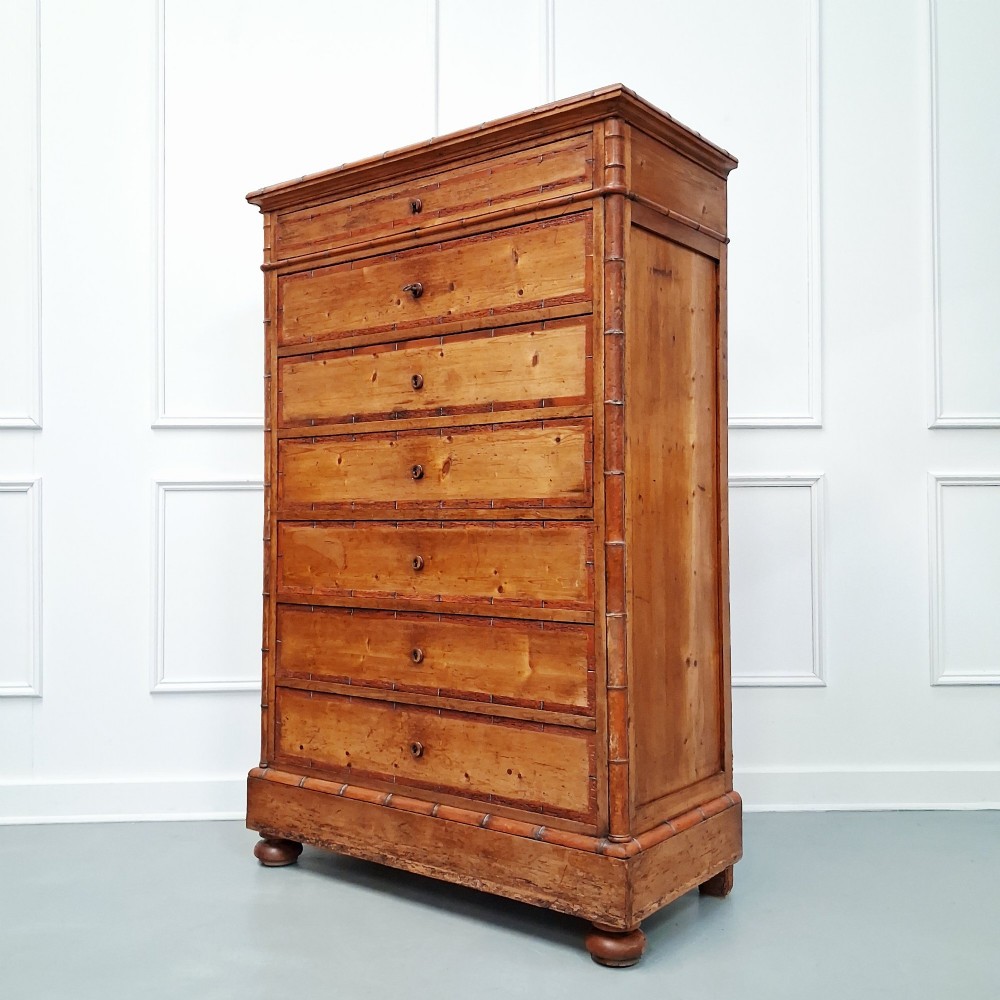 A tall 19th-century French wooden semainier chest featuring seven drawers framed by turned faux bamboo mouldings and supported by bun feet. View VIII