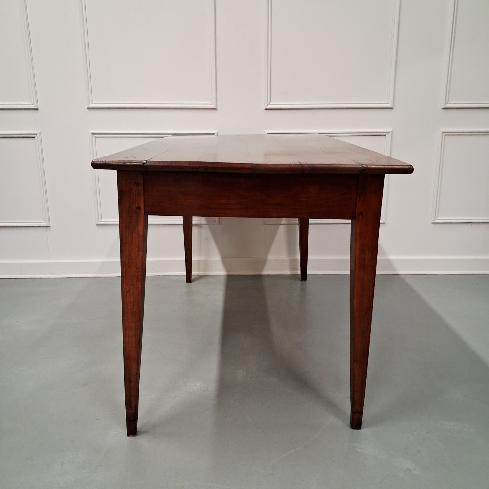 A late 19th-century French farmhouse dining table constructed from warm cherry wood featuring square tapered legs and an integrated frieze drawer. View II