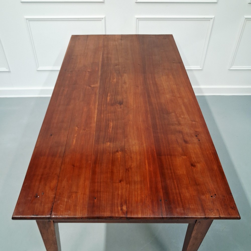 A late 19th-century French farmhouse dining table constructed from warm cherry wood featuring square tapered legs and an integrated frieze drawer. View III