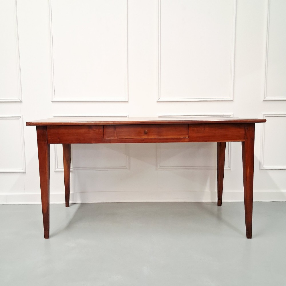 A late 19th-century French farmhouse dining table constructed from warm cherry wood featuring square tapered legs and an integrated frieze drawer. View IV