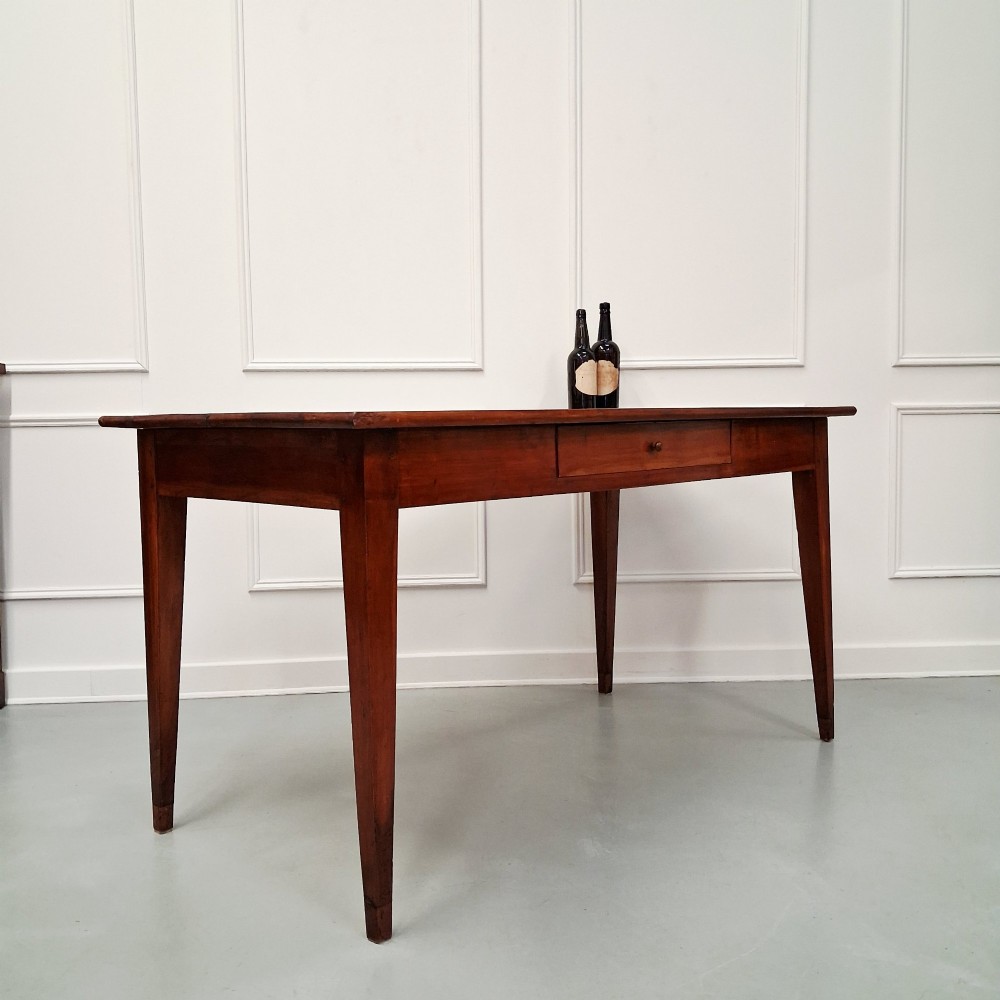 A late 19th-century French farmhouse dining table constructed from warm cherry wood featuring square tapered legs and an integrated frieze drawer. View VI