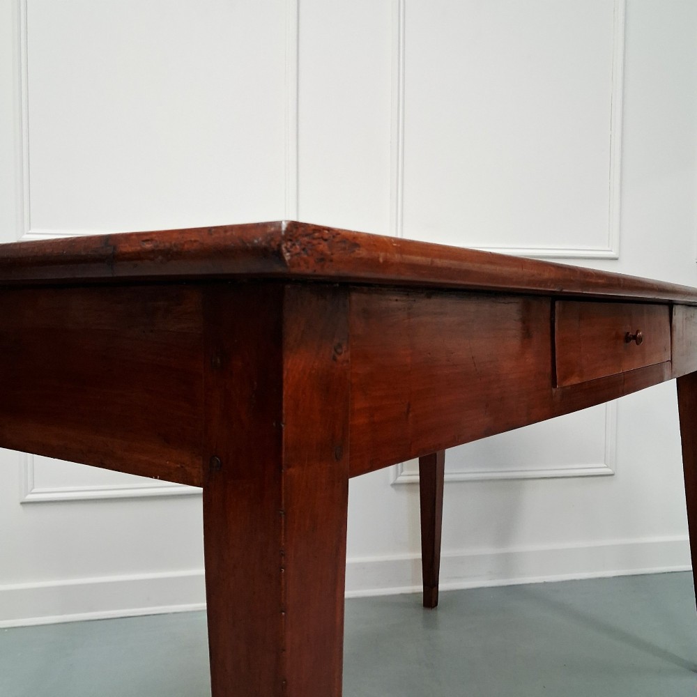 A late 19th-century French farmhouse dining table constructed from warm cherry wood featuring square tapered legs and an integrated frieze drawer. View VIII