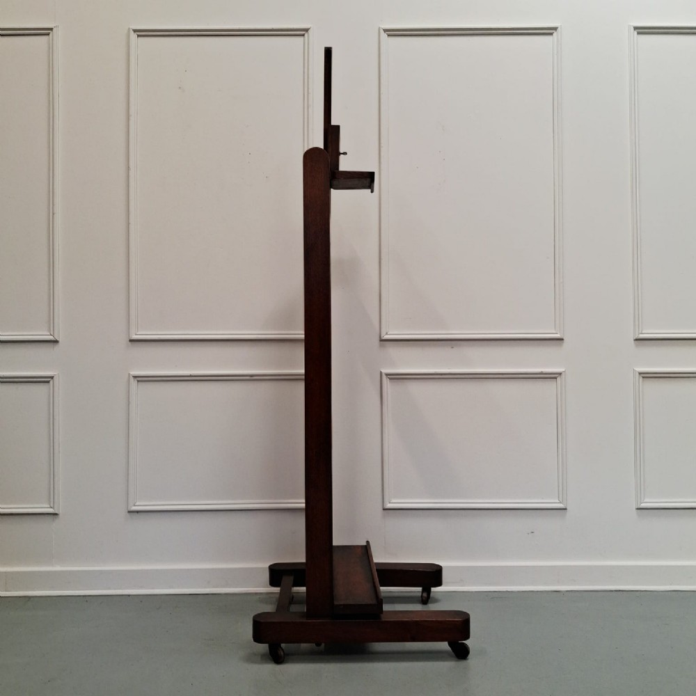 A dark oak French studio easel from circa 1890 featuring an adjustable vertical shaft, horizontal support shelf, and caster feet. View V