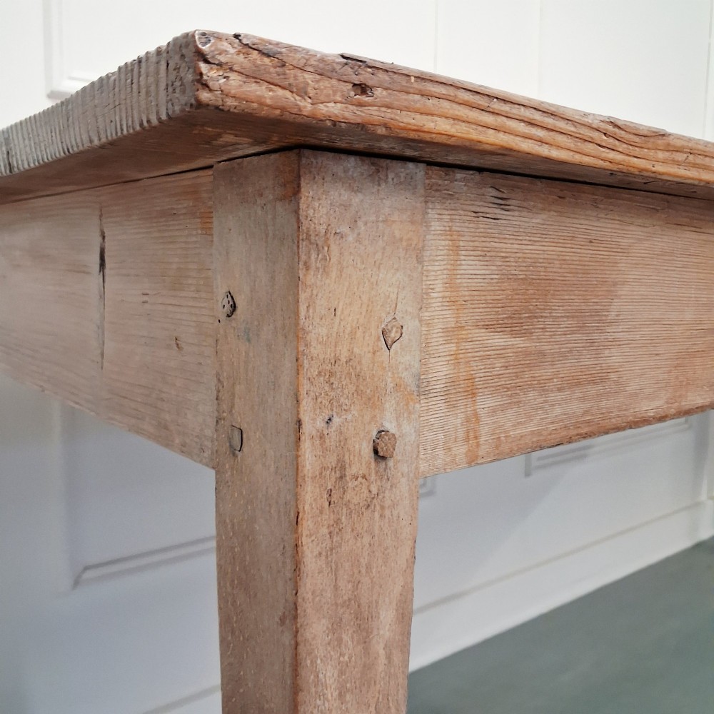 A long antique pine dining table featuring a solid plank top, deep side apron, and four tapered square legs. View IV