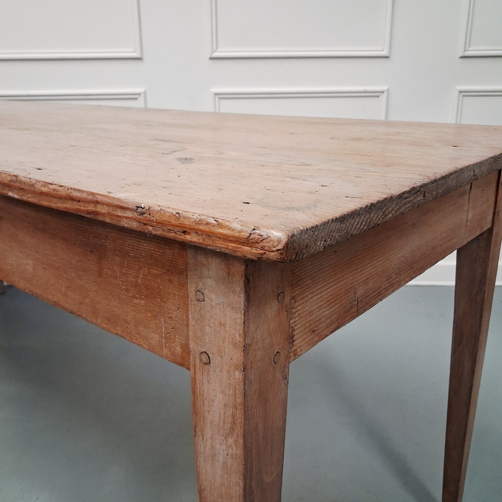 A long antique pine dining table featuring a solid plank top, deep side apron, and four tapered square legs. View VIII