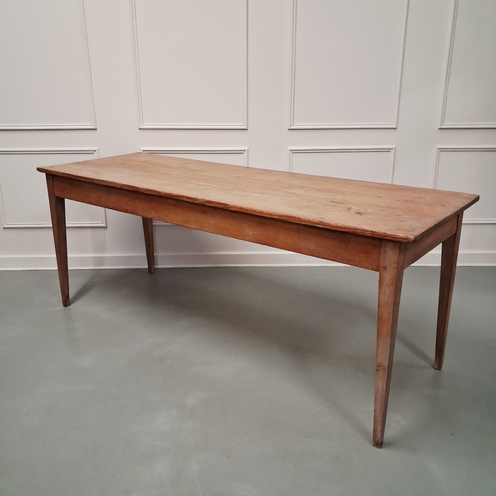 A long antique pine dining table featuring a solid plank top, deep side apron, and four tapered square legs. View IX