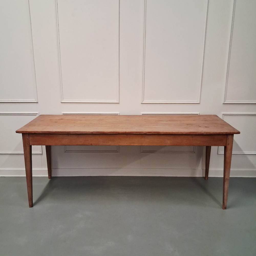 A long antique pine dining table featuring a solid plank top, deep side apron, and four tapered square legs. View X