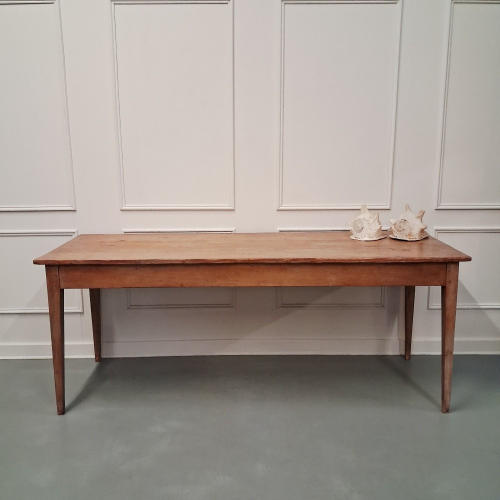 A long antique pine dining table featuring a solid plank top, deep side apron, and four tapered square legs. View XII