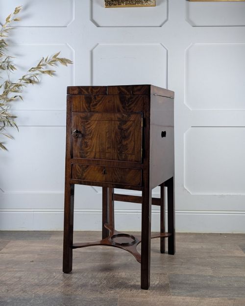 fig 2. A Georgian Cuban mahogany fold-away washstand featuring an upright mirror, opened side leaves, a central cupboard, a lower drawer, and an X-frame stretcher.