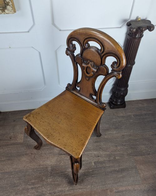 fig 1. A Victorian carved solid oak hall chair featuring an openwork shield back, a solid timber seat, and shaped cabriole front legs.