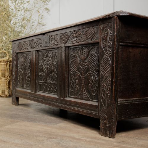 fig 2. A dark oak panelled chest featuring detailed floral and foliage relief carvings, a central panel inscribed TS 1690, and an iron lockplate.