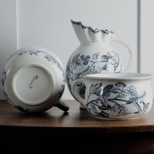 fig 1. An early 20th-century white ceramic wash set featuring a large ewer and two chamber pots decorated with a black botanical blackberry transferware pattern.