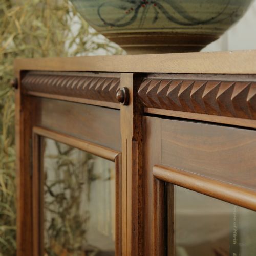 fig 2. An early 20th-century low double-section wooden bookcase featuring glazed doors with carved diamond border trim and three internal shelf levels filled with books.