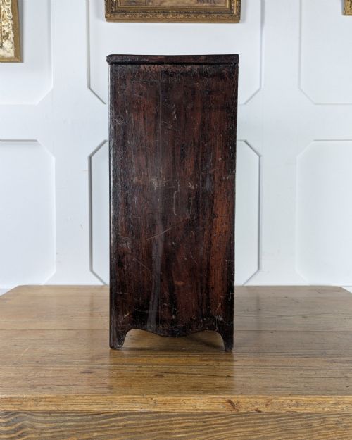 fig 2. A 19th-century miniature wooden chest of drawers with a dark stained finish, two small top drawers over three long drawers, turned knobs, and brass escutcheons.