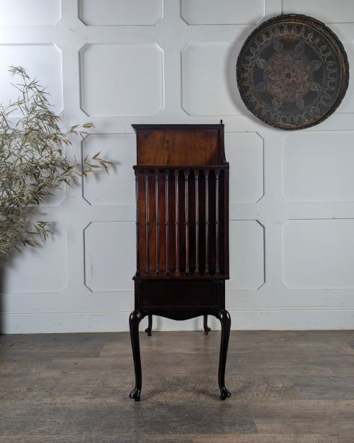 fig 2. An early 20th-century mahogany music cabinet featuring a central glazed door flanked by turned spindle galleries, set above two drawers on cabriole legs.