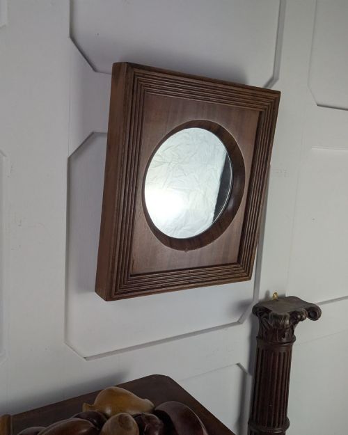 fig 1. A square dark mahogany frame featuring stepped outer mouldings and a central circular mirror reflection.