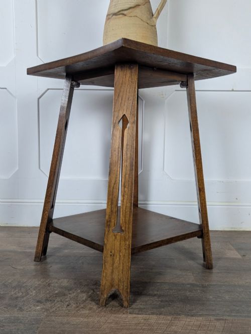 fig 2. A solid oak Art Nouveau side table featuring splayed legs with spade-shaped cutouts and a lower square undertier shelf.