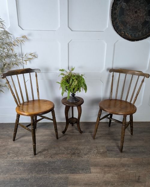 fig 1. A pair of early twentieth-century wooden Dinco penny chairs featuring spindle backs, turned legs, curved stretchers, and shaped seats.