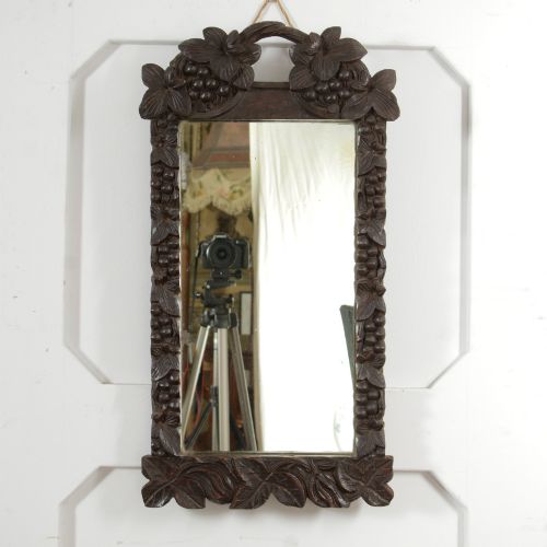 fig 1. A rectangular nineteenth-century dark oak wall mirror featuring hand-carved leaf and grape motifs around the wooden frame.