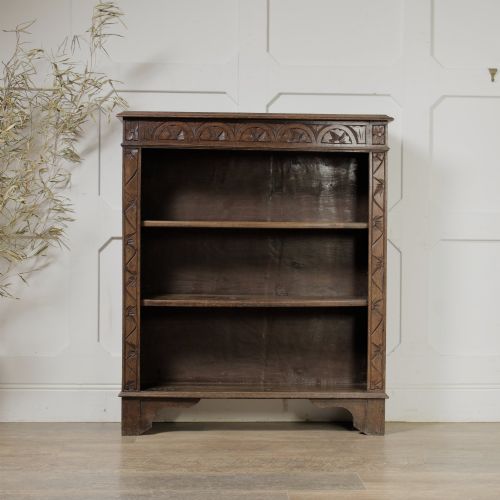 fig 2. An early 20th-century dark oak open bookcase featuring a carved lunette frieze and three tiers of shelving.