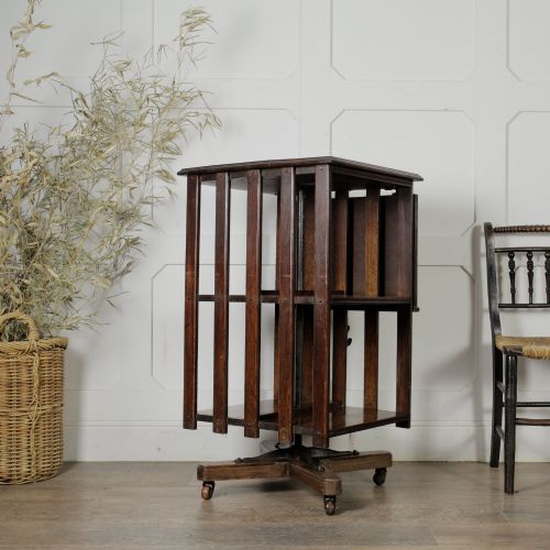 fig 2. An Edwardian dark oak revolving bookcase featuring vertical slats, multiple shelf tiers, an adjustable folding reading rest, and a quadruped base on castors.