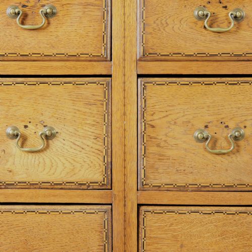 fig 1. A solid honey-coloured oak dresser featuring a top section with open shelving and small side cupboards, set upon a base with six drawers and brass swan-neck handles.