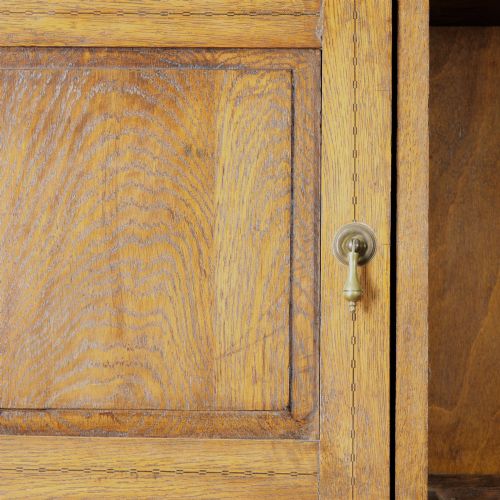 fig 2. A solid honey-coloured oak dresser featuring a top section with open shelving and small side cupboards, set upon a base with six drawers and brass swan-neck handles.