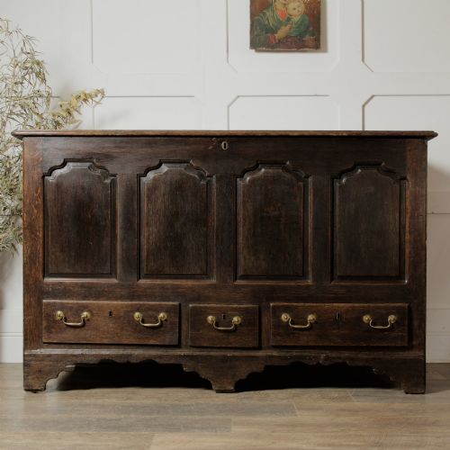 fig 1. A large 18th-century dark oak mule chest featuring four arched fielded panels, three bottom drawers with brass drop handles, and a shaped apron.