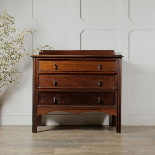 fig 1. An Edwardian mahogany chest featuring three graduated drawers with drop handles, fluted side pilasters, and a low upstand.