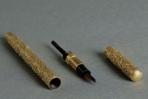 fig 2. An antique Mabie Todd Swan fountain pen with a detailed chased rolled gold barrel, unscrewed cap, and dark ebonite section with exposed nib.