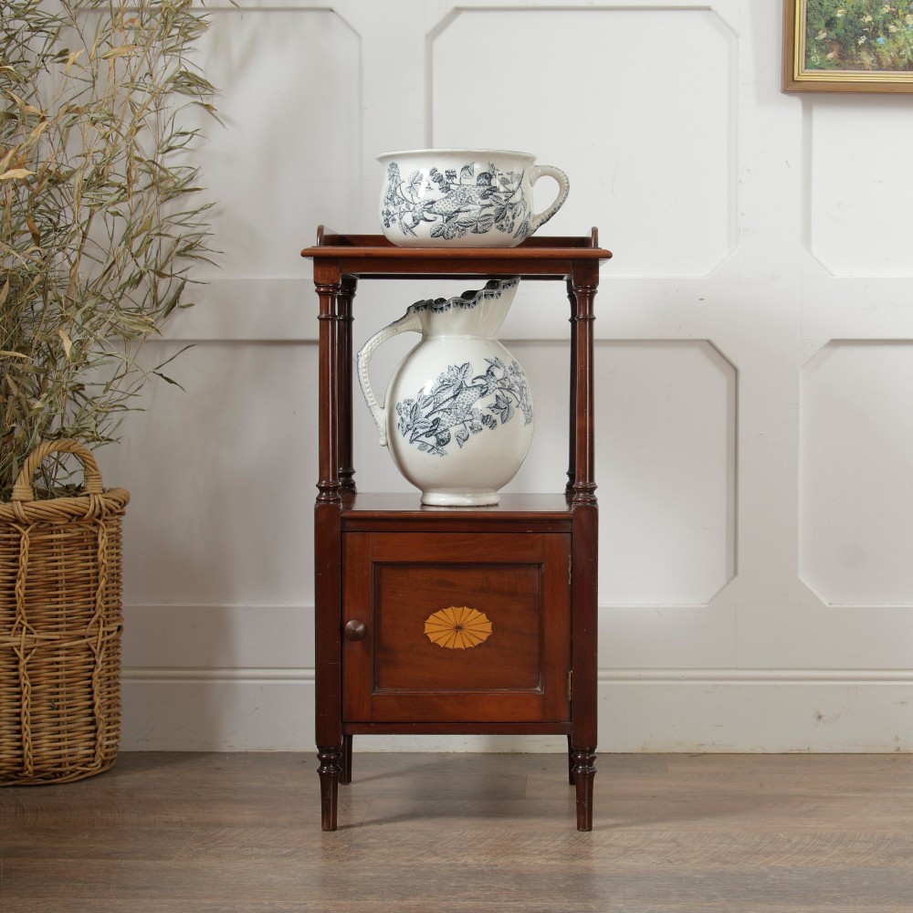 A Victorian mahogany pot cupboard with an open upper shelf supported by turned columns, sitting above a single-door cupboard adorned with a central marquetry inlay. View II