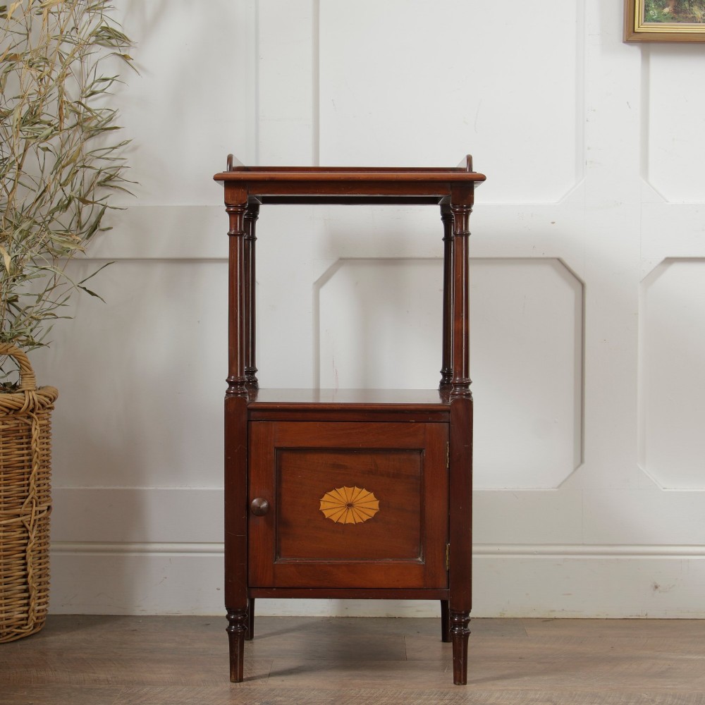 A Victorian mahogany pot cupboard with an open upper shelf supported by turned columns, sitting above a single-door cupboard adorned with a central marquetry inlay. View V