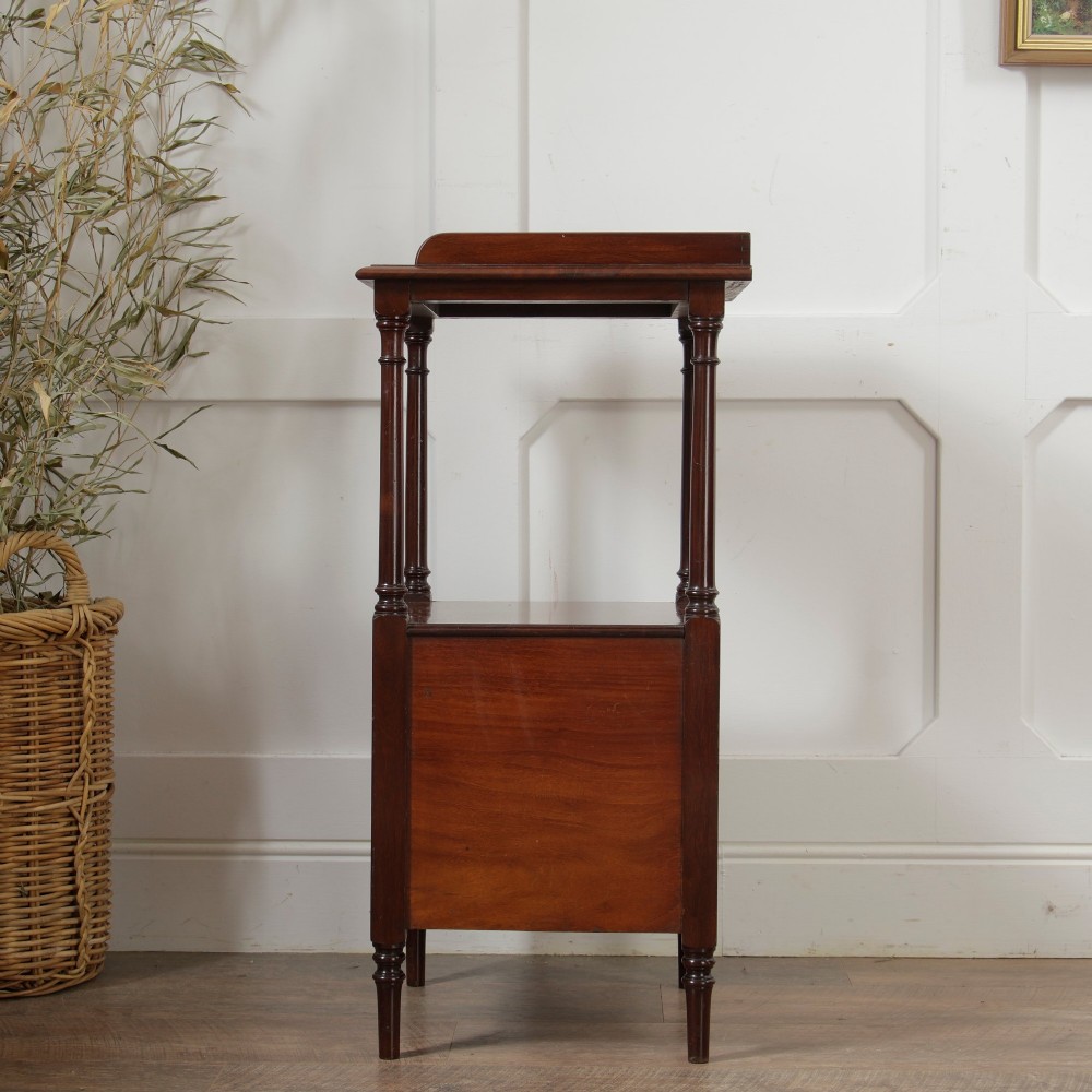 A Victorian mahogany pot cupboard with an open upper shelf supported by turned columns, sitting above a single-door cupboard adorned with a central marquetry inlay. View VI