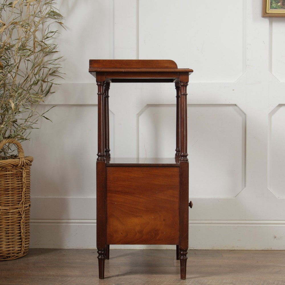 A Victorian mahogany pot cupboard with an open upper shelf supported by turned columns, sitting above a single-door cupboard adorned with a central marquetry inlay. View VIII