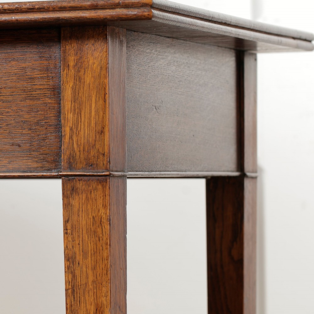 A George III Georgian oak side table featuring a single drawer with a brass handle plate and four square tapered legs. View IV