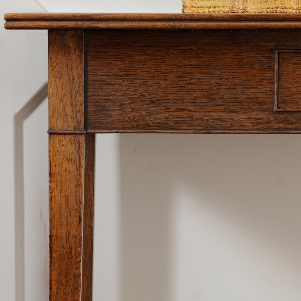 A George III Georgian oak side table featuring a single drawer with a brass handle plate and four square tapered legs. View X